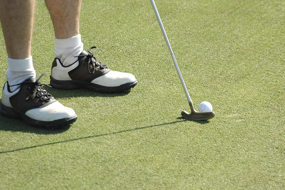 A golfer about to put on a fake grass putting green